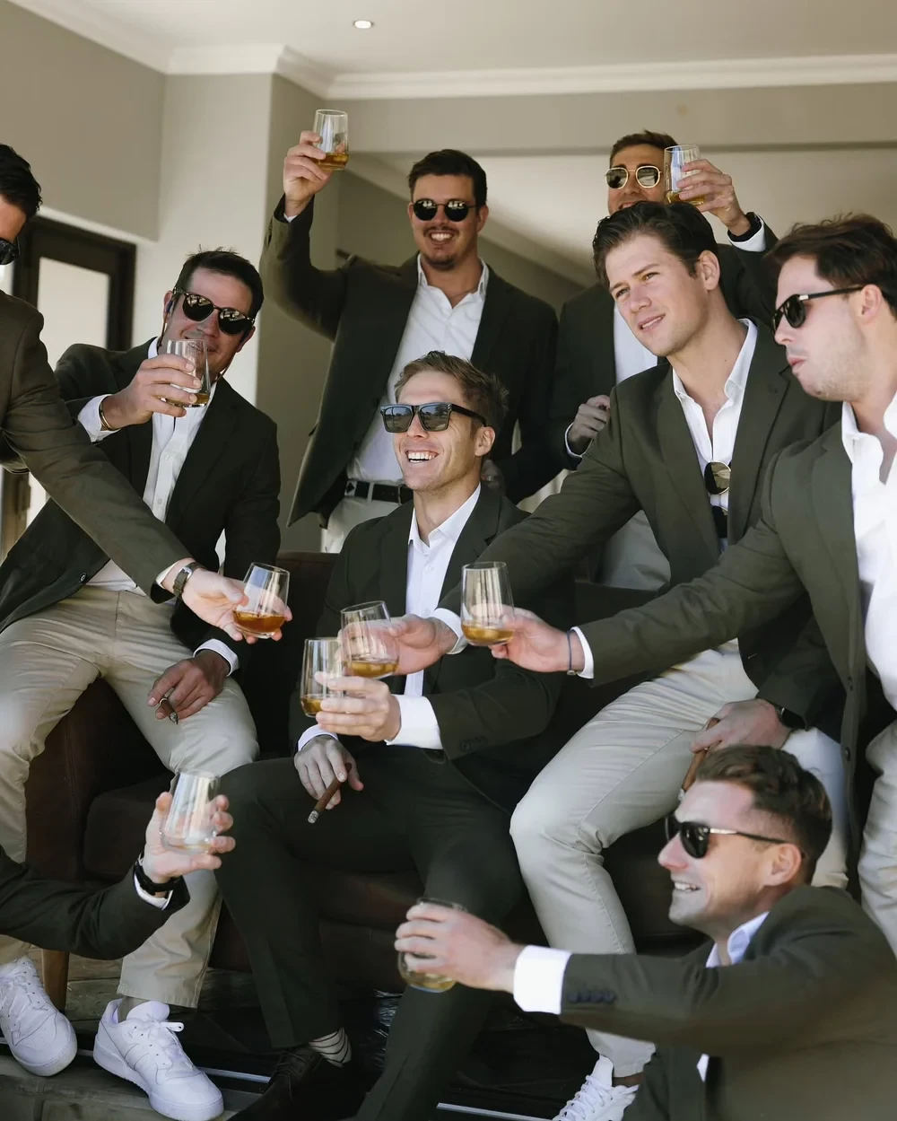 A group of friends in dark jackets and sunglasses raising drinks